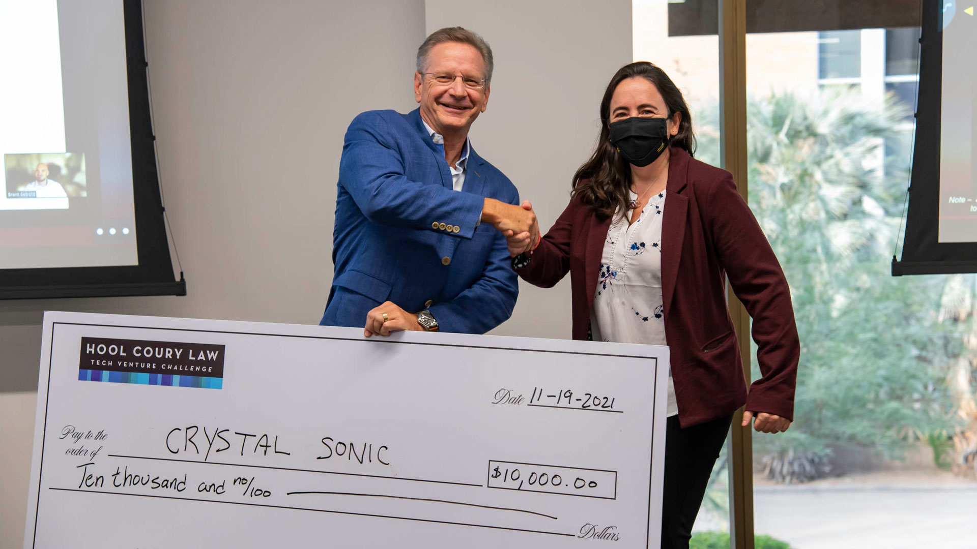 Mariana Bertoni receives a check from Michael Hool for seed funding for her venture, Crystal Sonic.