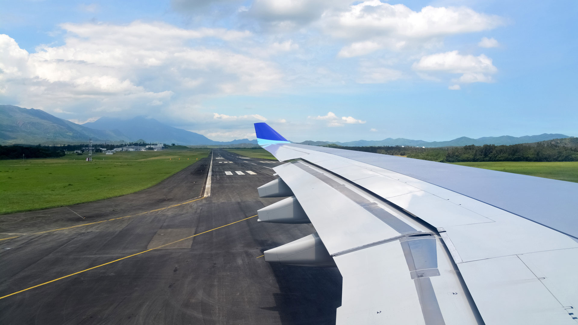 A photo of a plane wing over a runway.