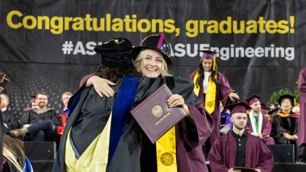 A student and faculty member celebrate at graduation.