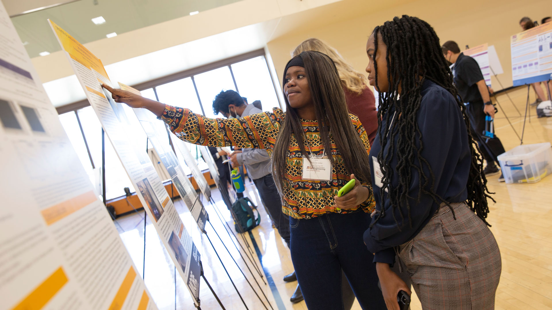 Students look at a research poster and discuss findings at the FURI Symposium