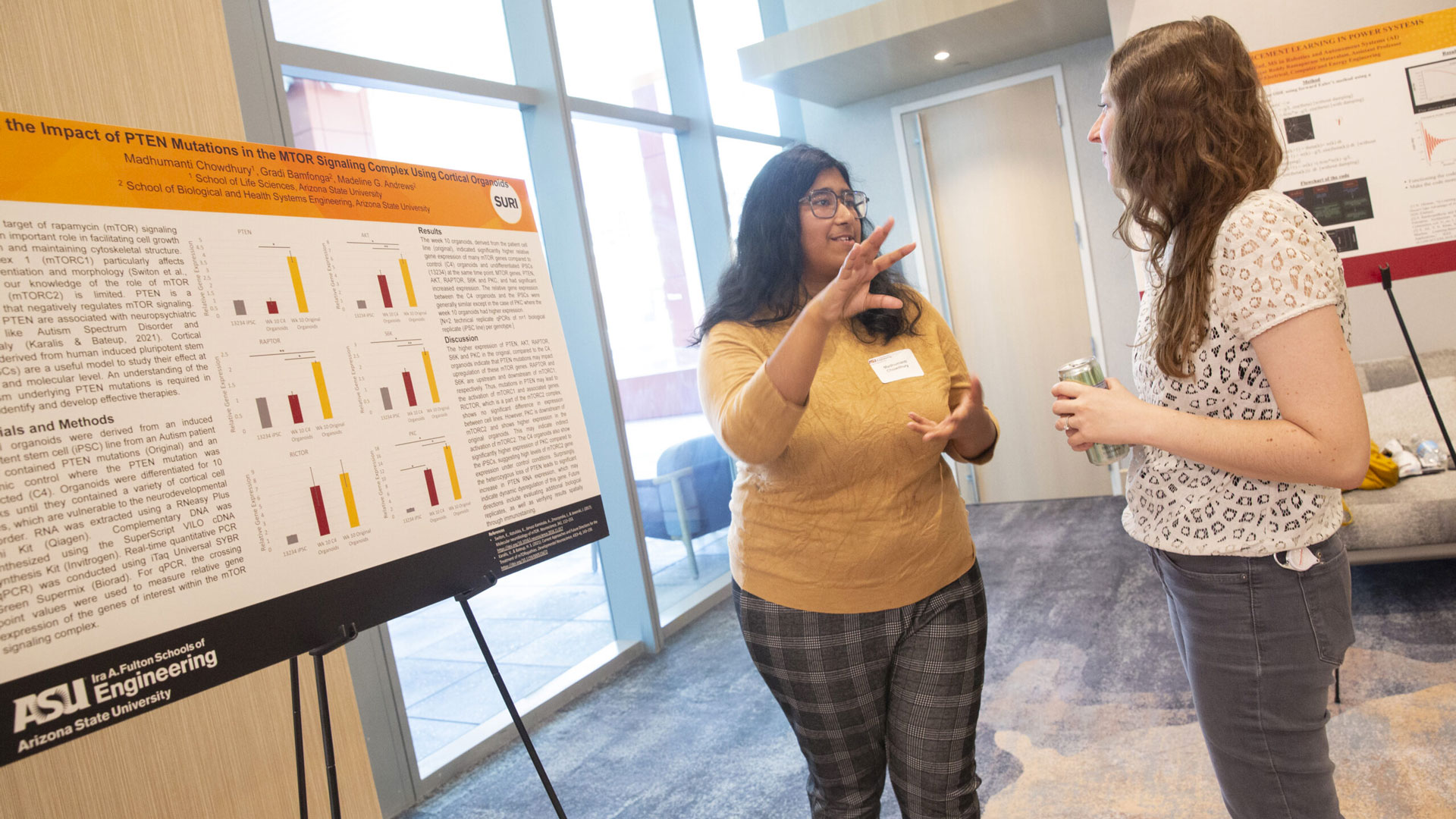 Students discuss research in front of a poster at a SURI event.