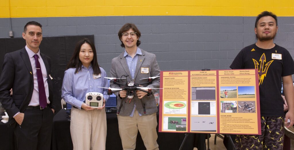 Students standing next to a poster presenting their senior team project