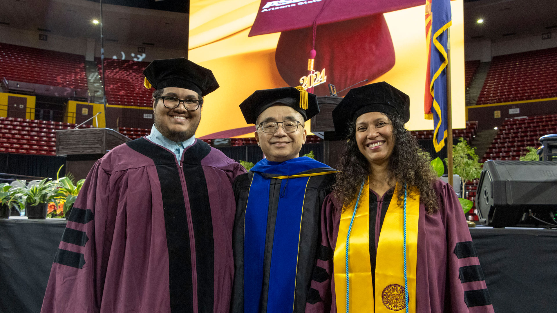 A professor and two doctoral graduates pose at the ASU Engineering Graduate Convocation ceremony.